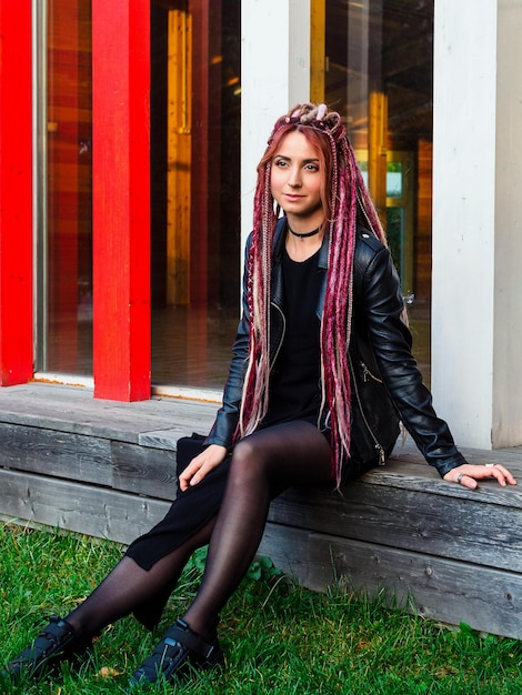 Portret van een mooie jonge vrouw met lange dreadlocks en staartjes in zwarte kleding buitenshuis