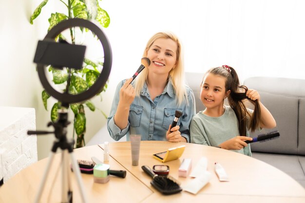 Portret van een mooie jonge vrouw, modevlogger of blogger die schoonheidsproducten voor opnamevideo bekijkt om te delen op sociale media. Cosmetisch concept. Vlog maken met een make-up tutorial.