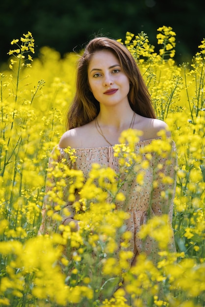Portret van een mooie jonge vrouw omringd door koolzaadbloemen