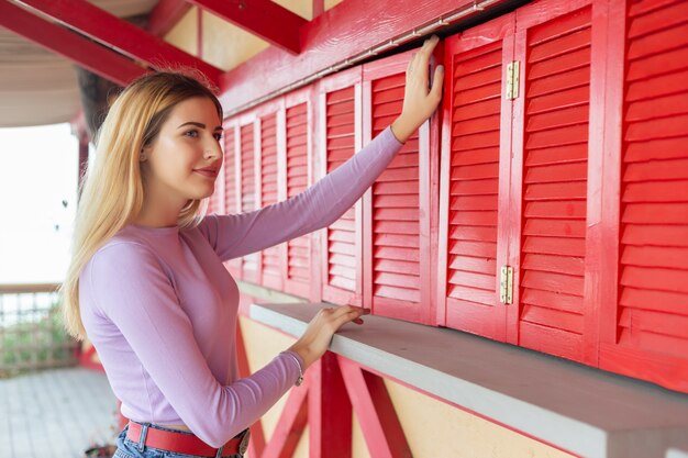 Portret van een mooie jonge vrouw op de achtergrond van een rode houten muur