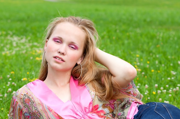 Portret van een mooie jonge vrouw op het gras in de zomer