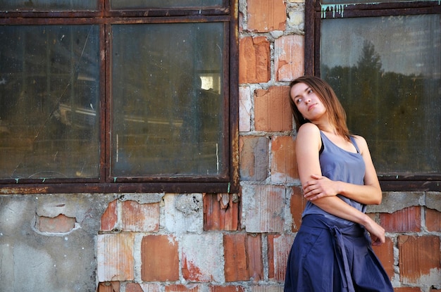 Portret van een mooie jonge vrouw tegen de achtergrond van een oude muur en ramen