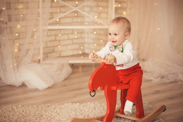 Portret van een mooie kleine babyjongen die een schommelende hert berijdt