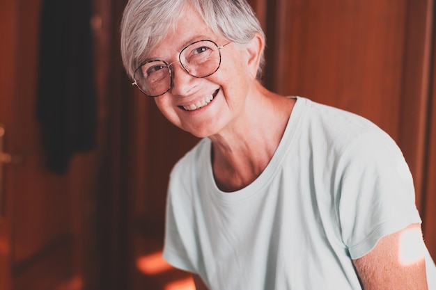 Portret van een mooie lachende oudere vrouw met wit haar die naar de camera kijkt en zich goed voelt