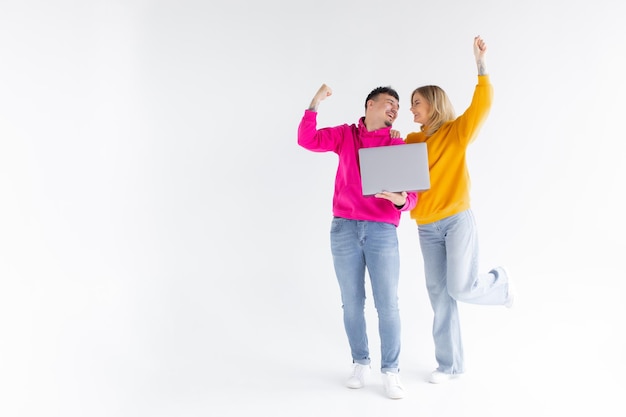 Portret van een mooie man en vrouw die een zilveren laptop vasthoudt terwijl ze geïsoleerd op een witte achtergrond staan