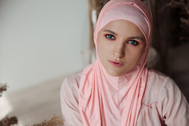 Portret van een mooie moslim arabische vrouw die een roze hijab draagt, kijkt naar de camera