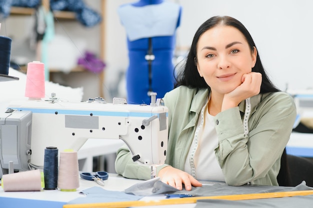 Portret van een mooie naaister die een meetlint draagt en in een textielfabriek werkt