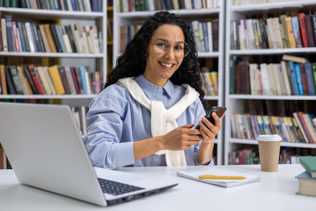 Portret van een mooie Spaanse studente in een universiteitsbibliotheek tussen boeken van een vrouw met