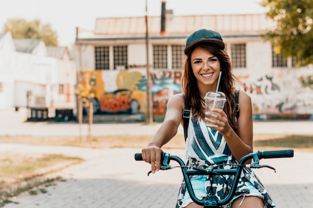 Portret van een mooie stedelijke jonge vrouw met een fiets.