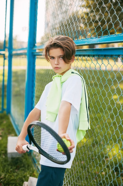 Portret van een mooie tiener die zich met een tennisracket en een bal in zijn handen bevindt