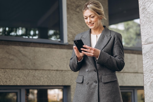 Portret van een mooie volwassen zakenvrouw glimlachend en pratend aan de telefoon op de moderne stedelijke achtergrond