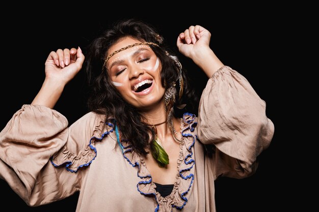 Portret van een mooie vrolijke jonge brunette vrouw die tribale kleding en accessoires draagt die geïsoleerd staan, dansend