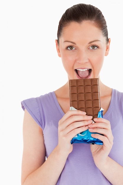 Portret van een mooie vrouw die een chocoladeblok eet terwijl status