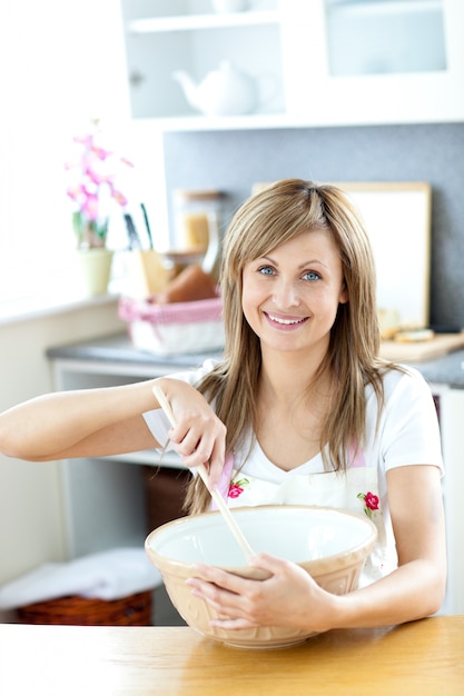 Portret van een mooie vrouw die een maaltijd in de keuken voorbereidt