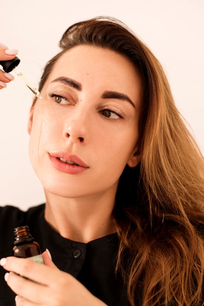 Portret van een mooie vrouw die haar huid hydrateert. De huid na de ingreep is stralend.