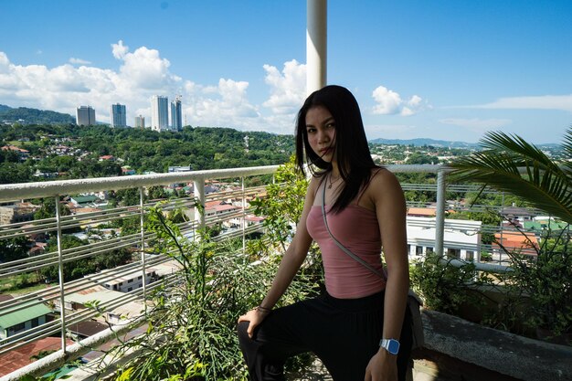 Portret van een mooie vrouw die op het balkon tegen de lucht staat