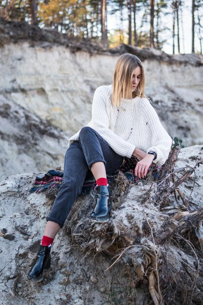 Portret van een mooie vrouw die op het zand zit en naar haar polshorloge kijkt