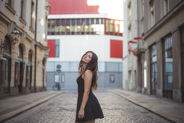 Portret van een mooie vrouw die op straat staat te midden van gebouwen in de stad