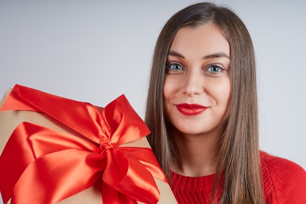 Portret van een mooie vrouw in een rode trui met een geschenkdoos close-up