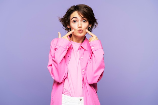 Foto portret van een mooie vrouw in een stijlvol roze shirt die naar de camera kijkt en geïsoleerd poseert