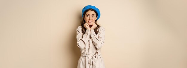 Portret van een mooie vrouw in een trendy outfit die haar gezicht aanraakt en er dromerig en verlangend uitziet