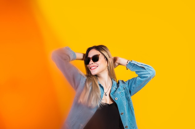 Portret van een mooie vrouw in zonnebril en gele achtergrond.