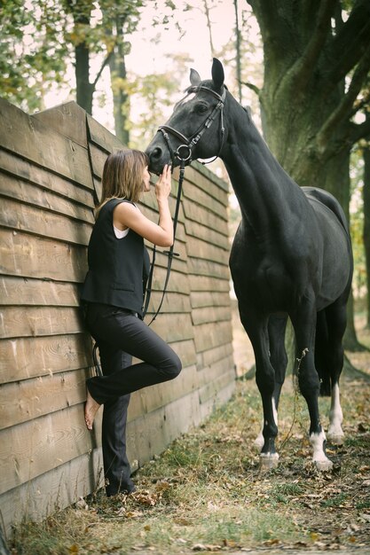 Portret van een mooie vrouw met bruin haar, gekleed in een zwart en zwart paard buiten Dagschot