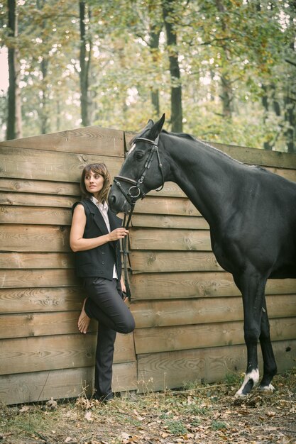 Portret van een mooie vrouw met bruin haar, gekleed in een zwart en zwart paard buiten Dagschot