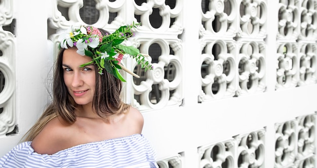 Portret van een mooie vrouw met een compositie van natuurlijke bloemen op haar hoofd