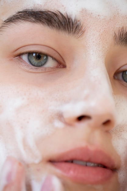 Foto portret van een mooie vrouw met een heldere huid die het gezicht wast met schuimreiniger