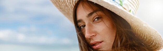 Portret van een mooie vrouw met een hoed op het strand op de achtergrond van de oceaan tijdens de vakantie