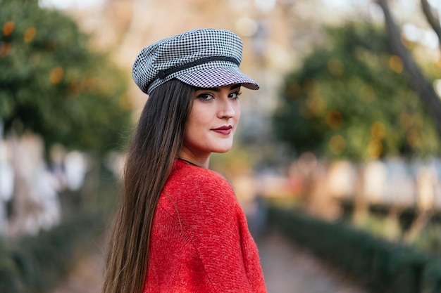 Foto portret van een mooie vrouw met een hoed tegen de achtergrond van enkele bomen