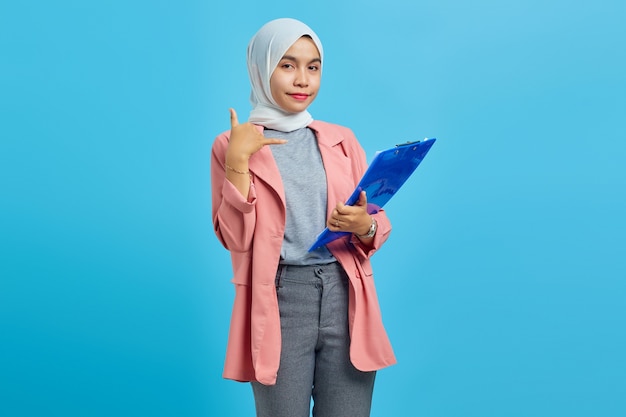 Portret van een mooie vrouw met een map die staat en belt op blauwe achtergrond