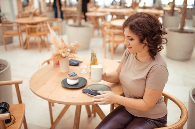 Portret van een mooie vrouw met een mok koffie in haar handen in een stadscafé