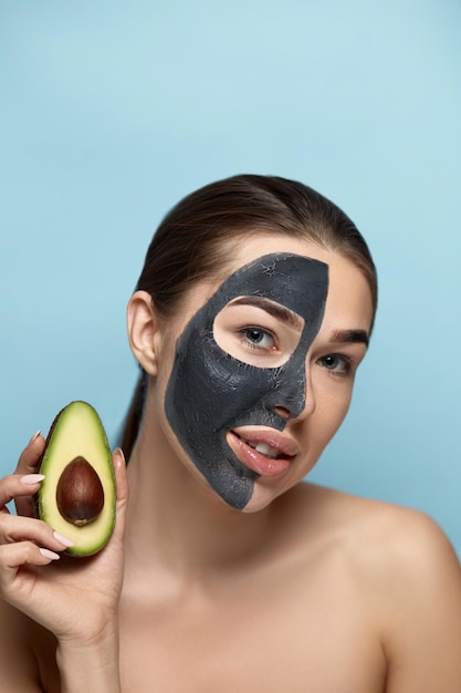 Portret van een mooie vrouw met een zwart masker van klei op het gezicht