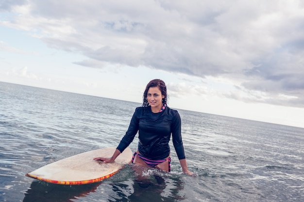 Portret van een mooie vrouw met surfplank in water