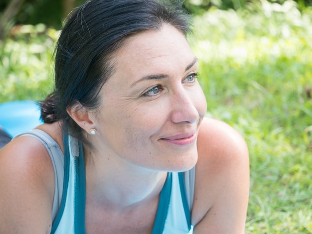 Portret van een mooie vrouw van middelbare leeftijd, liggend op een gras