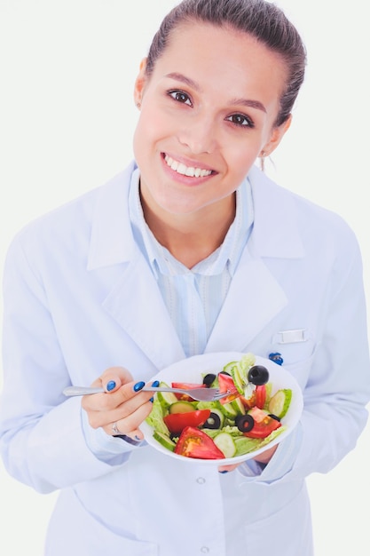 Portret van een mooie vrouwelijke arts die een bord met verse groenten houdt Vrouwelijke artsen