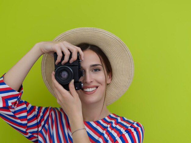 Portret van een mooie vrouwelijke fotograaf die van dichtbij fotografeert. Zeg kaas. Jonge lachende vrouw met camera geïsoleerd op groene achtergrond