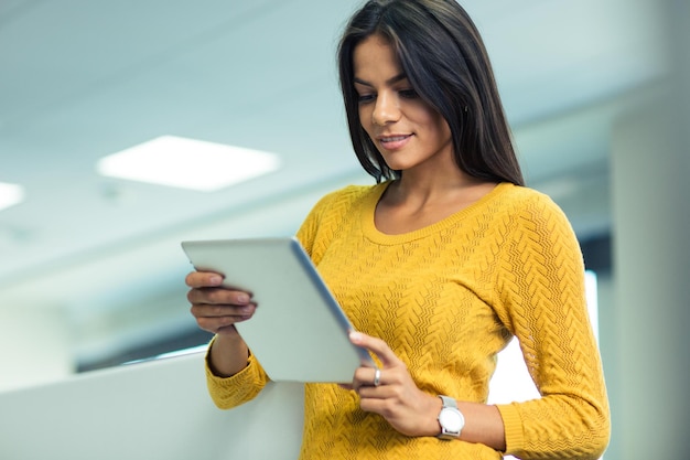 Portret van een mooie zakenvrouw die tabletcomputer op kantoor gebruikt