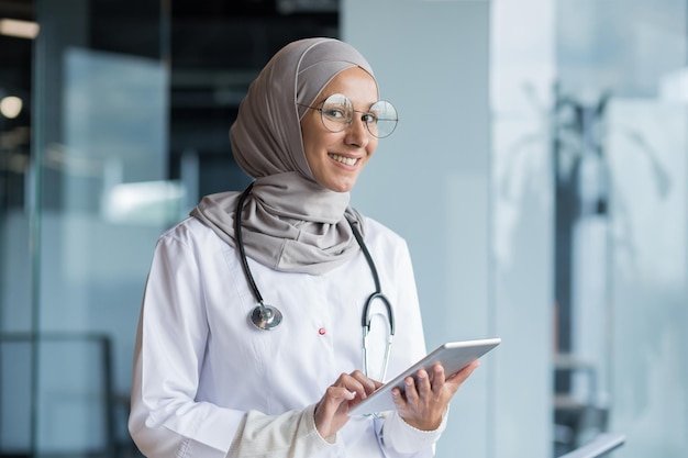 Portret van een moslim vrouwelijke arts in een hijab met een tablet in haar handen de dokter werkt in de