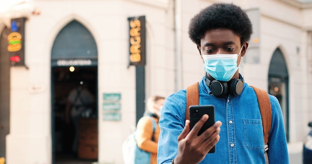 Portret van een multiraciale serieuze man met een beschermend masker die rustig naar de camera kijkt en vac...