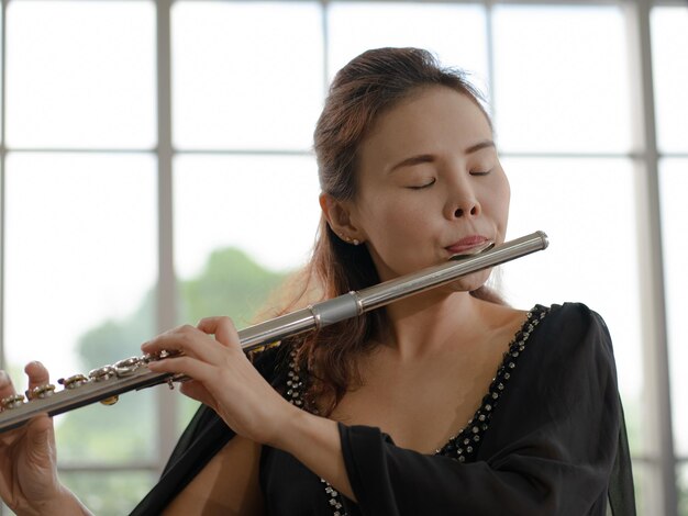 Foto portret van een muzikant die fluit speelt in een kamer