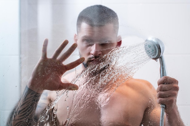 Portret van een naakte man die een douche neemt in de badkamer mannelijke hygiëne routine sexy man met een nat gespierd lichaam