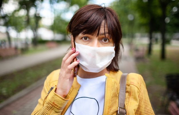 Portret van een niet-geïdentificeerde trieste vrouw van middelbare leeftijd in het witte beschermend masker poseren