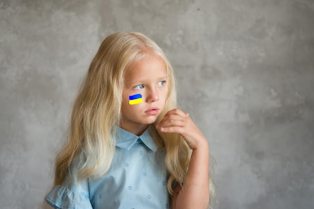Portret van een Oekraïens meisje met een geschilderde vlag op haar wang in gele en blauwe kleuren van Oekraïne