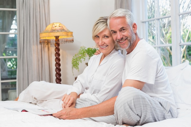 Portret van een ontspannen gelukkig volwassen paar met boek in bed