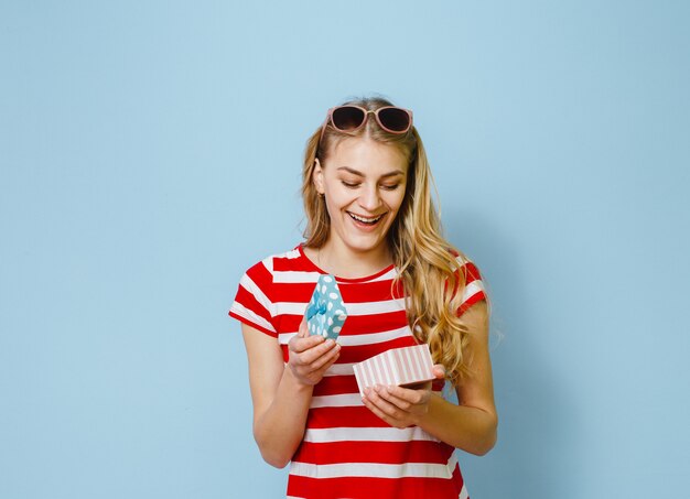 Portret van een opgewonden jonge mooie blondevrouw die een gift houden en gelukkig