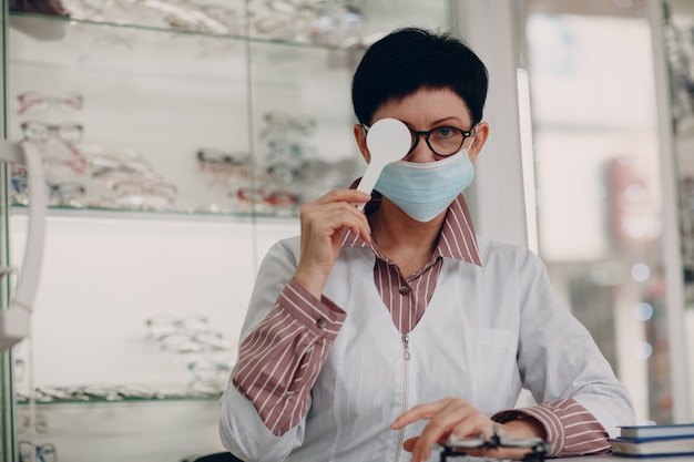 Portret van een optometrist oftalmoloog volwassen vrouw van middelbare leeftijd die een beschermend medisch gezichtsmasker draagt.