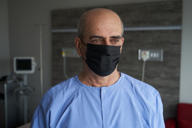 Portret van een oude man, 70 jaar oud, in een medisch masker